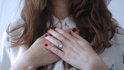 Woman puts her hands where her heart are across her chest