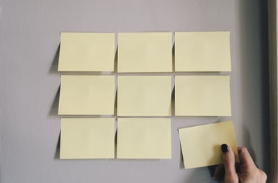 Hand adds a post-it to a wall